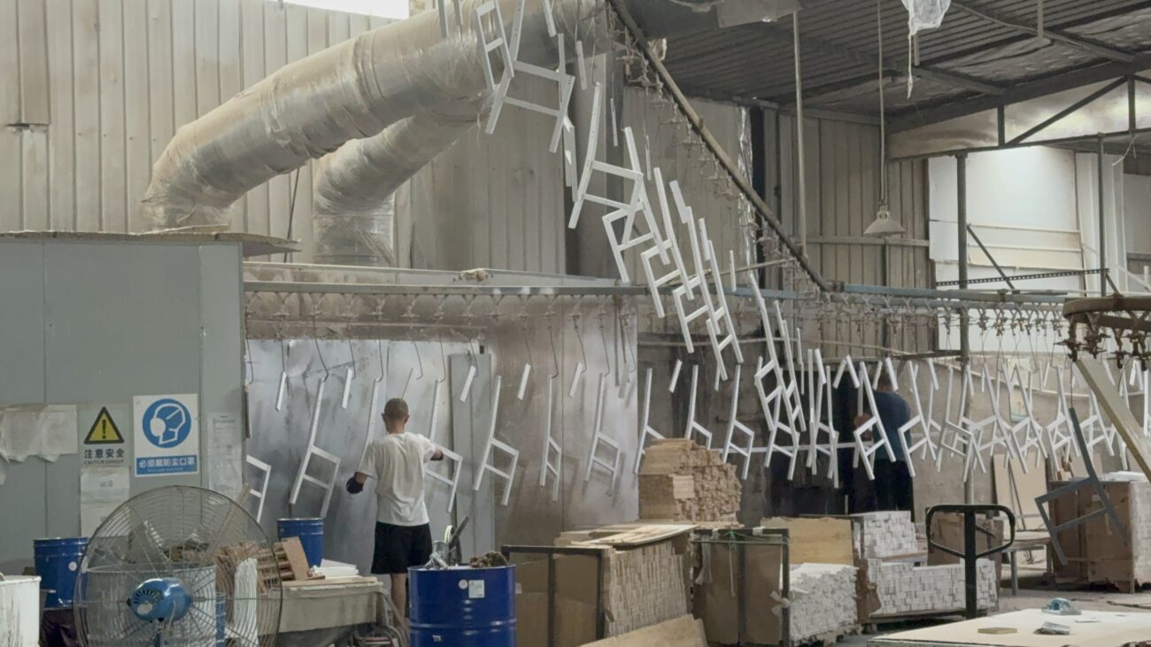 Factory worker applying wood finishing process in spray booth